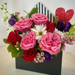 Envelope arrangement with mixed half dozen red and pink roses and beautiful accents of pink, white, and purple